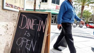 Un hombre camina junto a un 'Cena en Openi' en el centro de West Palm Beach, Florida. Foto: EFE