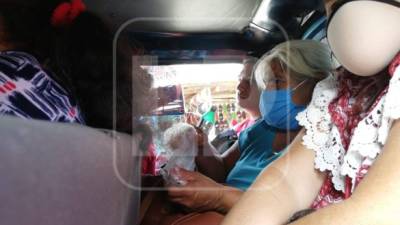 Un bus de la ruta Chamelecón-Centro, madre e hijo viajan con la mascarilla en la barbilla y comparten un jugo, mientras que el ciudadano de atrás consume una bebida.