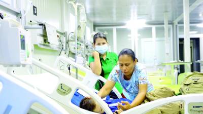 <b>Una mujer cuida de su hijo hospitalizado por dengue en el hospital Mario Rivas. Foto: Melvin Cubas.</b>