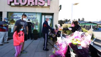 MERRICK, NEW YORK - MAY 10: Elizabeth Mcginn works the cashier stand outside the Flowers by Voegler store on May 10, 2020 in Merrick, New York. Theresa Soto is the owner of Flowers by Voegler. She and her staff have prepared to work in front of her store to sell floral arrangements on Mothers Day. Due to the coronavirus COVID-19 pandemic, no customers are allowed in the store. Al Bello/Getty Images/AFP== FOR NEWSPAPERS, INTERNET, TELCOS & TELEVISION USE ONLY ==