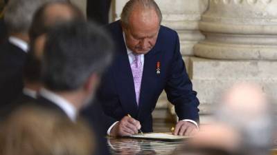 El rey Juan Carlos al firmar su abdicación en favor de su hijo Felipe.