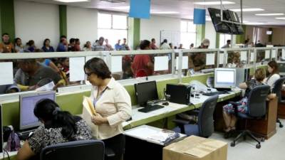 Dos empleadas asisten desde la ventanilla a un contribuyente en las oficinas de la DEI en San Pedro Sula.