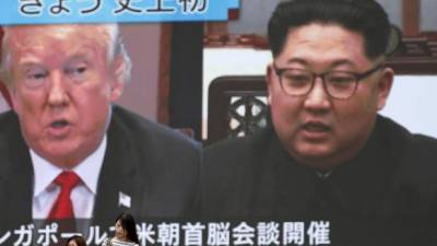 Una persona pasa frente a una gran pantalla con la transmisión de la cumbre entre Kim Jong-un y Donald J. Trump. EFE/Archivo