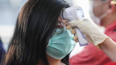 A una mujer que lleva una máscara protectora se le hace un examen de temperatura mientras ingresa al lugar del desfile de Chingay en Singapur, el 31 de enero de 2020.EFE / EPA / WALLACE WOON / Archivo