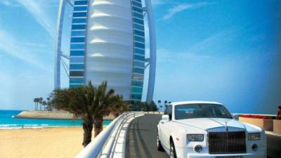 Un automóvil de lujo circula por las calles de Dubai. Al fondo, el lujoso hotel Burj Al Arab Jumeirah.