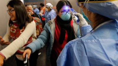 Personal médico toma la temperatura a los viajeros que llegan al aeropuerto Jorge Chávez de la ciudad de Lima.