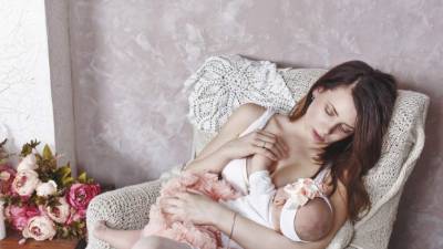 Happy young family, a mother breastfeeds little daughter. The concept of happiness of motherhood.