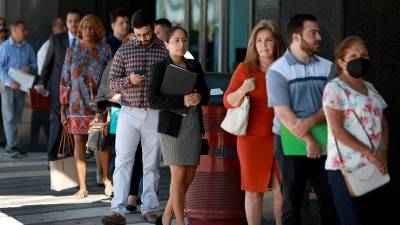 Decenas de personas hacen fila para entrevistas en una feria de empleo en Miami, Florida.