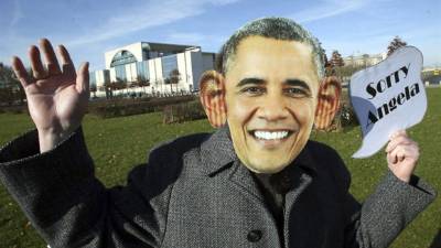 Un activista de la 'Oficina para las medidas inusuales' disfrazado de Barack Obama sostiene una pancarta en la que se puede leer 'Lo siento, Angela' delante de la Cancillería en Berlín (Alemania) hoy, jueves 31 de octubre de 2013