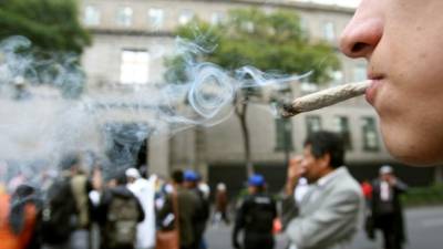 Un joven fuma marihuana durante una protesta en las afueras de la Suprema Corte de Justicia de la Nación, en Ciudad de México. Foto archivo EFE.