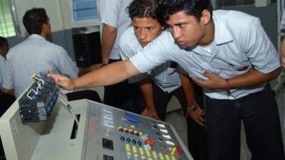 Dos estudiantes del Centro Técnico Honduras Corea revisan una máquina.