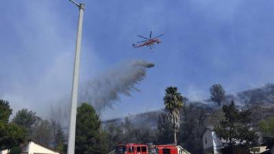 Los bomberos de California combaten los incendios forestales con helicópteros ante los fuertes vientos que alimentan el fuego en los condados de Ventura y Los Ángeles./AFP.