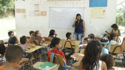 En la mañana, los alumnos de primero reciben clases en el patio de la escuela protegidos del sol por la sombra de un árbol.