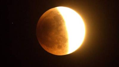 TOPSHOTSThe moon is halfway through a lunar eclipse over southern California as seen from Korea town, west of downtown Los Angeles early on April 15, 2014. The entire event was to be visible from North and South America, but sky watchers in northern and and eastern Europe, eastern Africa, the Middle East and Central Asia were out of luck, according to NASA. AFP PHOTO/JOE KLAMAR