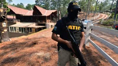 Un agente de la Atic resguarda la casa de campo de la ex primera dama Rosa Bonilla de Lobo. AFP