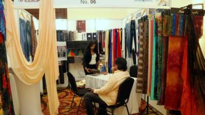 Una representante de la empresa india Rameshwar Textile Mills LTD muestra el catálogo de productos a un potencial cliente en San Pedro Sula. Foto: Amílcar Izaguirre