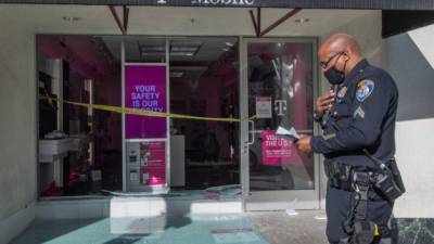 Un oficial de policía de Beverly Hills registra daños en una tienda T Mobile saqueada después de que los manifestantes protestaron por la muerte de George Floyd. AFP