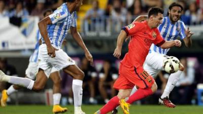 Leo Messi avanza con el balón ante los defensas del Málaga, el brasileño Weligton Robson Pena de Oliveira (i) y Sergio Sánchez.