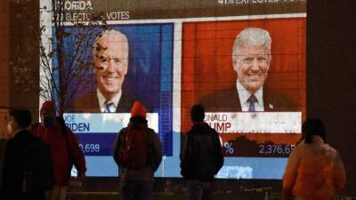 People watch a big screen displaying the live election results in Florida at Black Lives Matter plaza across from the White House on election day in Washington, DC on November 3, 2020. (Photo by Olivier DOULIERY / AFP)