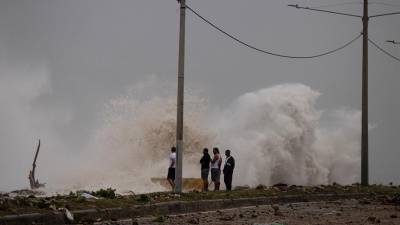 Unas personas observan el fuerte oleaje durante el paso del huracán Beryl, en el malecón de Santo Domingo, República Dominicana.