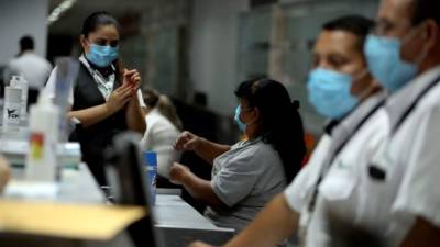 Empleados de líneas aéreas que funcionan en las instalaciones del Aeropuerto Internacional Toncontín se protegen con mascarillas hoy miércoles en Tegucigalpa.