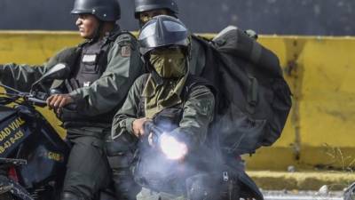 TOPSHOT - Members of the National Guard charge on opposition activists during protests against Venezuelan President Nicolas Maduro in Caracas on July 10, 2017. Venezuela hit its 100th day of anti-government protests Sunday, amid uncertainty over whether the release from prison a day earlier of prominent political prisoner Leopoldo Lopez might open the way to negotiations to defuse the profound crisis gripping the country. / AFP PHOTO / JUAN BARRETO