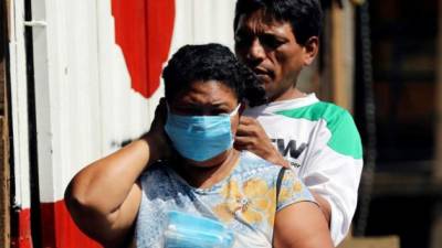 Un hombre ayuda a colocar una mascarilla a una mujer en un mercado el pasado lunes, en la ciudad de Comayagüela (Honduras). EFE/Gustavo Amador