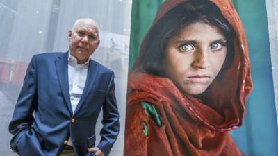 El fotógrafo estadounidense Steve McCurry posa junto a su fotografía, 'La niña afgana' (1984). EFE/Archivo