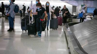 Travelers retrieve their luggage at Newark International Airport on November 21, 2020 in Newark, New Jersey. - Current US numbers -- more than a quarter of a million deaths have been reported -- have alarmed authorities enough to advise that people stay home for the November 26 Thanksgiving holiday, when Americans usually travel to be with their families. (Photo by Kena Betancur / AFP)