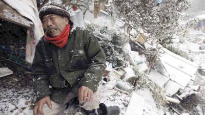 A sixty-six-year-old man Yoshikatsu Hiratsuka cries in front of his collapsed house with his mother still missing, possibly buried in the rubble, at Onagawa town in Miyagi prefecture on March 17, 2011. The official number of dead and missing after a devastating earthquake and tsunami that flattened Japan's northeast coast is approaching 15,000, police said. JAPAN OUT RESTRICTED TO EDITORIAL USE MANDARORY CREDIT 'AFP PHOTO / YOMIURI SHIMBUN' AFP PHOTO / YOMIURI SHIMBUN