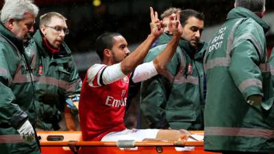 Así salió Walcott del campo en camilla y haciendo festo a aficionados del Tottenham.