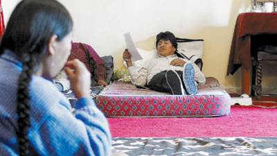 Bolivia's President Evo Morales reads a document during the third day of his hunger strike in La Paz, Saturday, April 11, 2009. Morales started a hunger strike Thursday to pressure Bolivia's Congress to approve a law that will allow the country's general elections to be held on Dec. 6, 2009. Morales is likely to be reelected then. The woman at left is an unidentified peasant leader who is also on hunger strike. (AP Photo/ Juan Karita)