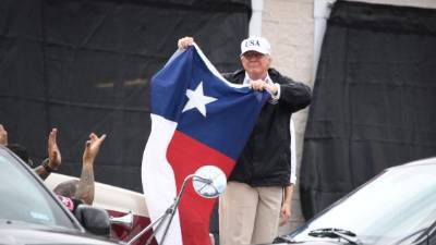 Trump ondeo una bandera de Texas prometiendo que el estado se recuperará 'muy pronto' de la devastadora tormenta. AFP.