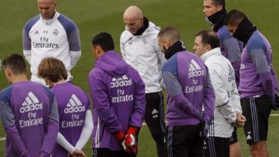 El técnico francés del Real Madrid, Zinedine Zidane (i), junto a su ayudante David Bettoni (c) y el delantero portugués Cristiano Ronaldo (d), junto al resto de la plantilla, guardan un minuto de silencio en recuerdo por las víctimas del accidente de avión ocurrido hoy en Colombia, en el que viajaban jugadores del equipo brasileño del Chapecoense, antes del inicio del entrenamiento realizado en la Ciudad Deportiva de Valdebebas. EFE