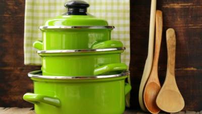 set of metal green pots cookware on a wooden background