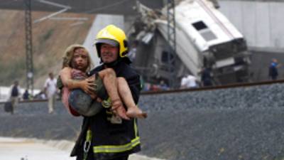 SPAIN OUTA picture taken on July 24, 2013 shows a fireman carrying an injured young girl following a train accident near the city of Santiago de Compostela. A train hurtled off the tracks on July 24 in northwest Spain killing at least 78 passengers and injuring more than 140, an official said today, the country's deadliest rail disaster in more than 40 years. AFP PHOTO / LA VOZ DE GALICIA / XOAN A. SOLER / MONICA FERREIROS