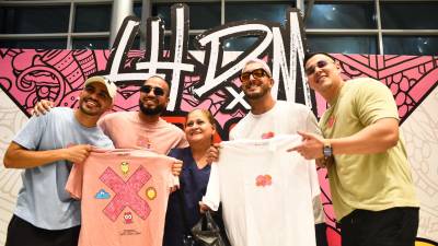 Carlos Zúniga, DJ Chaval, Fancony y JD posan junto con una de sus seguidoras y muestran los diseños de sus camisetas.