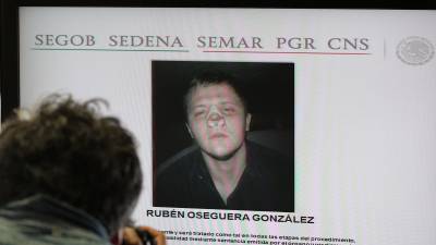 Un fotógrafo toma imágenes a una pantalla con el rostro de Rubén Oseguera González, alias el Menchito durante rueda de prensa en Ciudad de México.