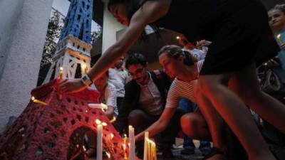 Varias personas encienden velas alrededor de una pequeña réplica de la torre Eiffel durante una vigila en memoria de los 74 adultos y 10 niños asesinados en el ataque perpetrado el pasado jueves en Niza.