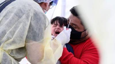 El hispano Jose Vatres y su hijo Aidin se sometieron a una prueba gratis de coronavirus en una escuela de Los Ángeles./AFP.