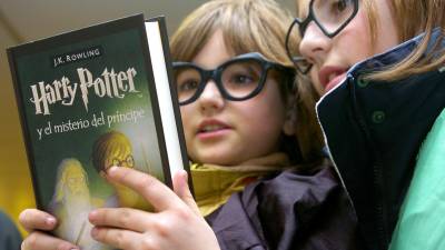Dos pequeñas mientras leen un libro de J. K. Rowling titulado Harry Potter y el misterio del príncipe.