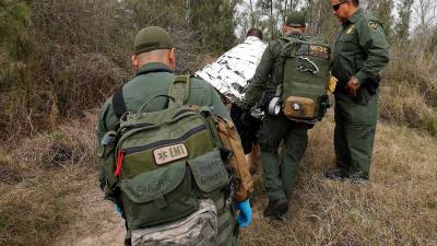 Un agente de la Patrulla Fronteriza de los Estados Unidos revisa médicamente a una persona sospechosa de cruzar el Río Grande para ingresar ilegalmente a los Estados Unidos en Texas.