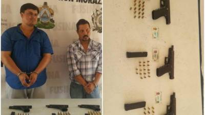 Dos de los individuos capturados junto a las armas decomisadas.