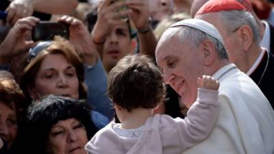 Pope Francis hugs a little boy as he visits San Gregorio Parish in Rome on April 6, 2014. AFP/PHOTO Filippo MONTEFORTE