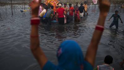An Indian Hindu devotee gestures as other devotees immerse an idol in the Yamuna river as part of the Durga Puja festival in New Delhi on October 13, 2013. Durga Puja commemorates the slaying of demon king Mahishasur by goddess Durga, marking the triumph of good over evil. AFP PHOTO/ Andrew Caballero-Reynolds