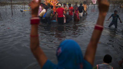 An Indian Hindu devotee gestures as other devotees immerse an idol in the Yamuna river as part of the Durga Puja festival in New Delhi on October 13, 2013. Durga Puja commemorates the slaying of demon king Mahishasur by goddess Durga, marking the triumph of good over evil. AFP PHOTO/ Andrew Caballero-Reynolds