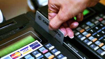 Una cajera pasa una tarjeta de crédito por una máquina POS.