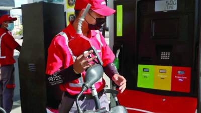 Empleado de una estación de servicio recargado combustible a una motocicleta.