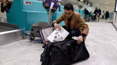 Un pasajero libio saca su computadora de su equipaje en el aeropuerto Túnez-Cartago, uno de los afectados por la prohibición.
