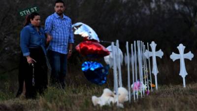 People pray at a row of crosses for each victim, after a mass shooting that killed 26 people in Sutherland Springs, Texas on November 6, 2017.A gunman wearing all black armed with an assault rifle opened fire on a small-town Texas church during Sunday morning services, killing 26 people and wounding 20 more in the last mass shooting to shock the United States. / AFP PHOTO / Mark RALSTON